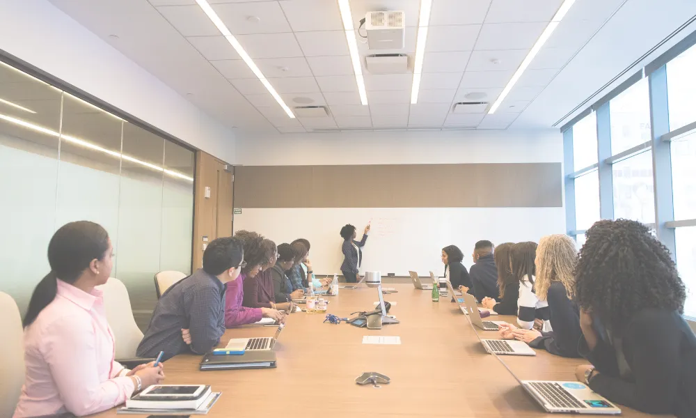 A woman leading a meeting at a whiteboard.